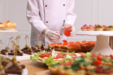Chef making sandwiches with red caviar for buffet, closeup