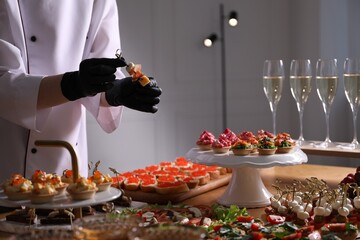 Chef arranging appetizers on buffet table, closeup
