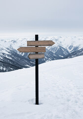 Naklejka premium A Blank Wooden Signpost Offering Choices in a Snowy Mountain Landscape