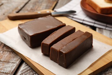 Pieces of tasty chocolate butter and knife on wooden table, closeup