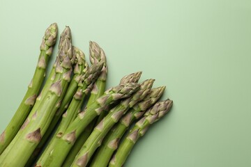 Fresh ripe raw asparagus on green background, closeup. Space for text