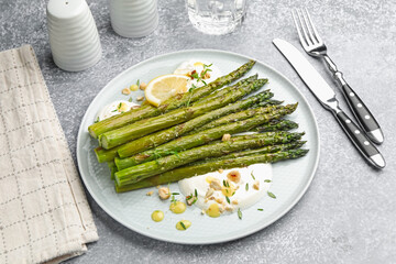 Tasty cooked asparagus served with lemon and sauce on grey table