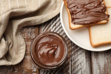 Tasty chocolate butter and slices of bread on color wooden table, flat lay