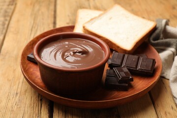 Tasty chocolate butter, pieces and bread on wooden table, closeup