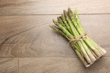 Fresh raw asparagus spears on wooden table, top view. Space for text