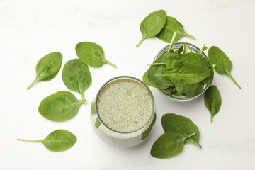 Tasty smoothie and spinach leaves on white marble table, flat lay