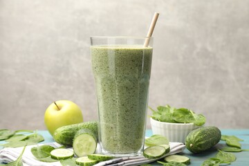 Tasty spinach smoothie and ingredients on light blue wooden table, closeup
