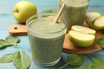 Tasty spinach smoothie and ingredients on light blue wooden table, closeup