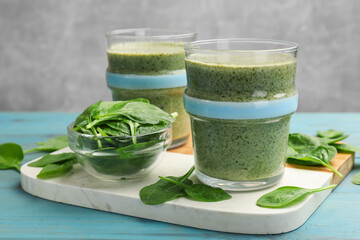 Tasty spinach smoothie and ingredients on light blue wooden table, closeup