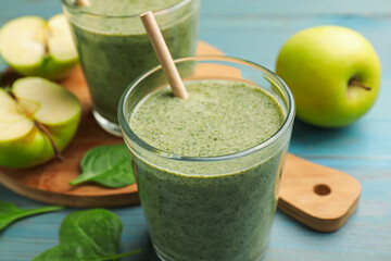 Tasty spinach smoothie and ingredients on light blue wooden table, closeup