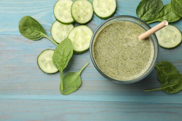Tasty spinach smoothie and ingredients on light blue wooden table, flat lay. Space for text
