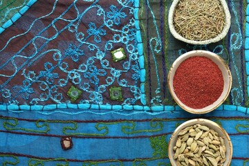 Different aromatic spices on blue tablecloth, flat lay. Space for text