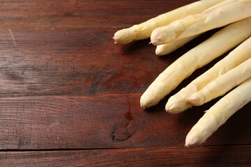 Many raw asparagus spears on wooden table, closeup, Space for text