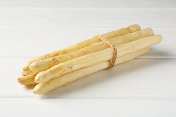 Bunch of raw asparagus spears on white wooden table, closeup