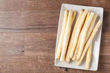 Raw white asparagus spears on wooden table, top view. Space for text