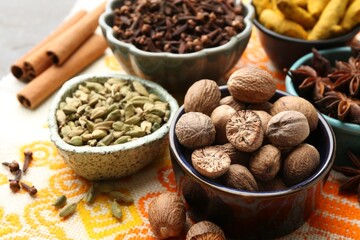 Different aromatic spices on orange tablecloth, closeup