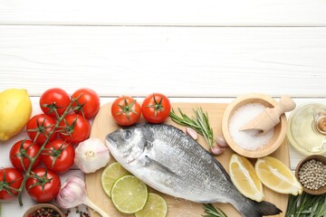 Fresh raw dourade fish with spices on white wooden table, flat lay and space for text. Seafood delicacies