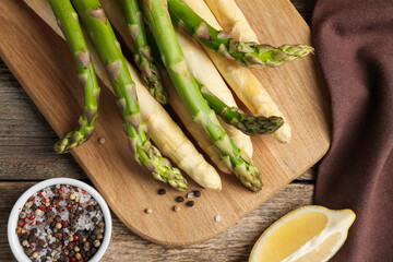 Different raw asparagus spears and spices on wooden table, flat lay
