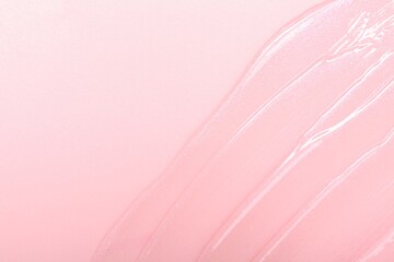 Sample of clear lip gloss on pink background, top view. Space for text
