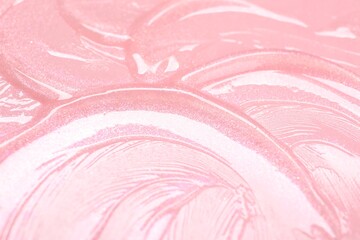 Sample of clear lip gloss on pink background, closeup