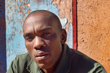 africa village, single african man headshot, in the township , tough manly look, standing outdoors...