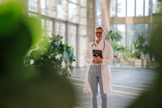 Female doctor using digital tablet in modern hospital lobby