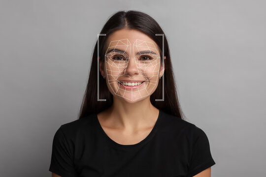 Facial recognition system. Scanning woman's face for authentication against light grey background