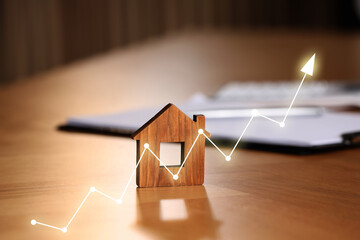 Increase in real estate value. House model and documents on table. Growing price represented by...