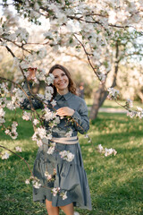 A delicate photo of a girl holding a blooming apple tree branch with white flowers in a sunny...
