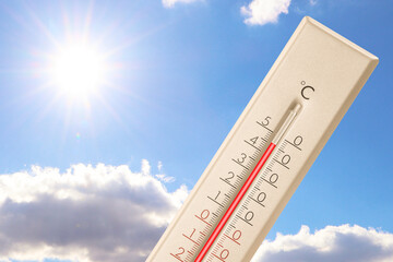 Extremely high temperature on thermometer against blue sky on sunny day. Summer weather