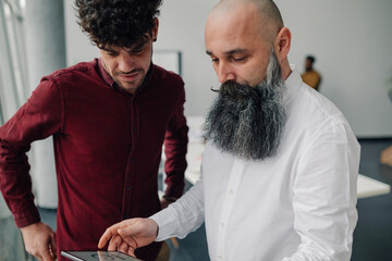 Two businessmen using tablet, discussing business strategy in office