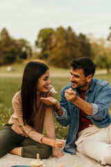 Couple sharing food, enjoying romantic picnic in park