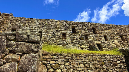 Ancient Inca Stone Wall with Windows at Machu Picchu under Bright Blue Sky
