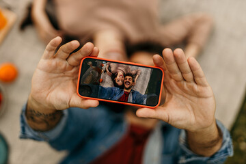 Young couple taking a selfie while lying on a blanket outdoors