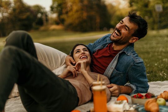 Happy couple laughing together during romantic picnic in park