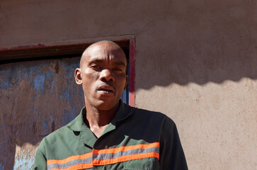 africa village, single african young man headgear hat, in the township , tough manly look, standing...