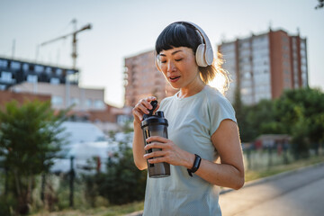 Mature japanese woman athlete drink protein shake after jogging