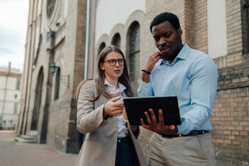 Business colleagues discussing worrisome news on tablet in front of church