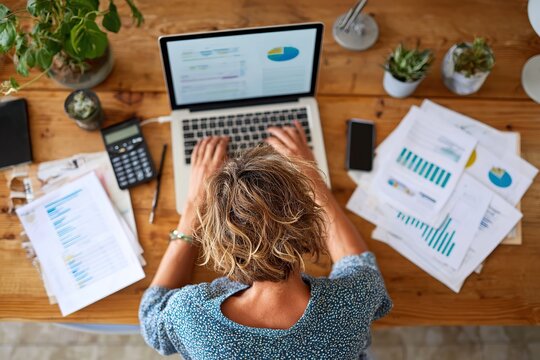 Businesswoman analyzes financial data while working on a laptop in a modern office space