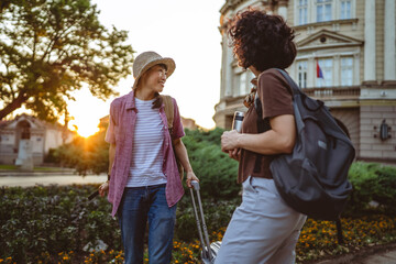 two beautiful women friends with suitcases discuss on the street