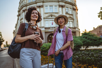 two beautiful women friends with suitcases discuss on the street