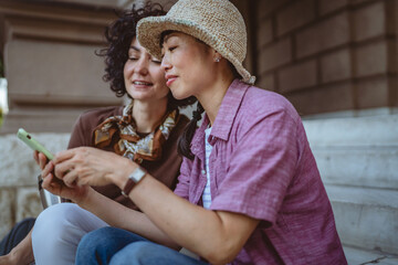 female tourist use mobile phone for directions while sit on staircase