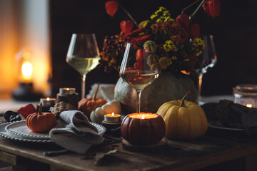 Atmospheric autumn elegant beautiful table setting with pumpkins for a wedding or thanksgiving family celebration. Fall decoration countryside rustic style, cozy home atmosphere , candles, wine