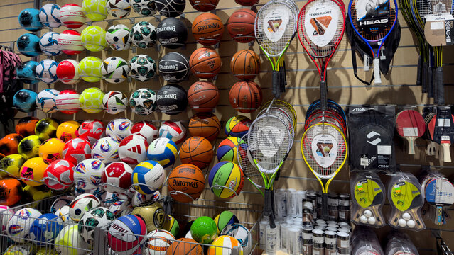 Warsaw, Poland - June 28, 2025: Colorful display of various sports balls and tennis rackets in a store