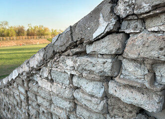 Close-up of a rough stone wall with aged, textured bricks. The surface showcases natural wear and cracks, ideal for use as a grunge background or building texture in design projects.