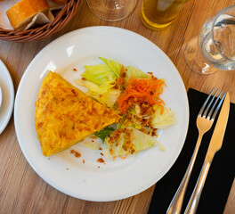 Traditional Spanish potato tortilla triangular pieces served with green salad.