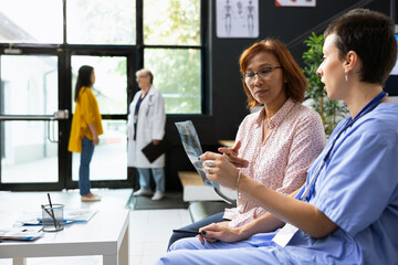Medical assistant reviewing X ray scans with asian patient during a checkup appointment. Hospital...
