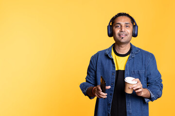 Joyous person listening to music and having fun dancing, enjoying hot beverage. Upbeat young guy...