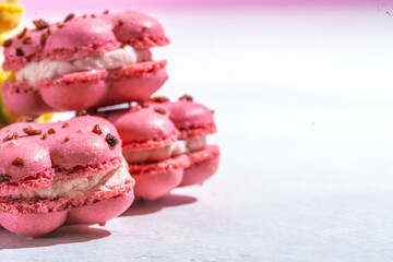 french macaron or macaroon cookies in strawberry pink on white marble, close up, copy space