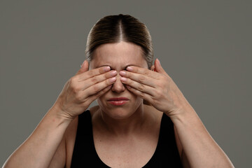 The woman covers her eyes with both hands, feeling the pain in her eyes.